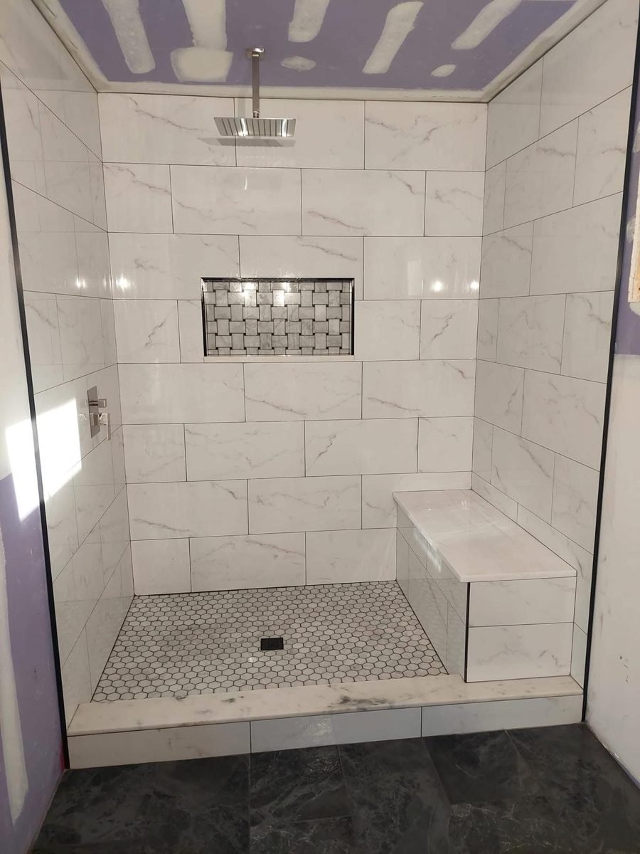 Shower with white tile and bench